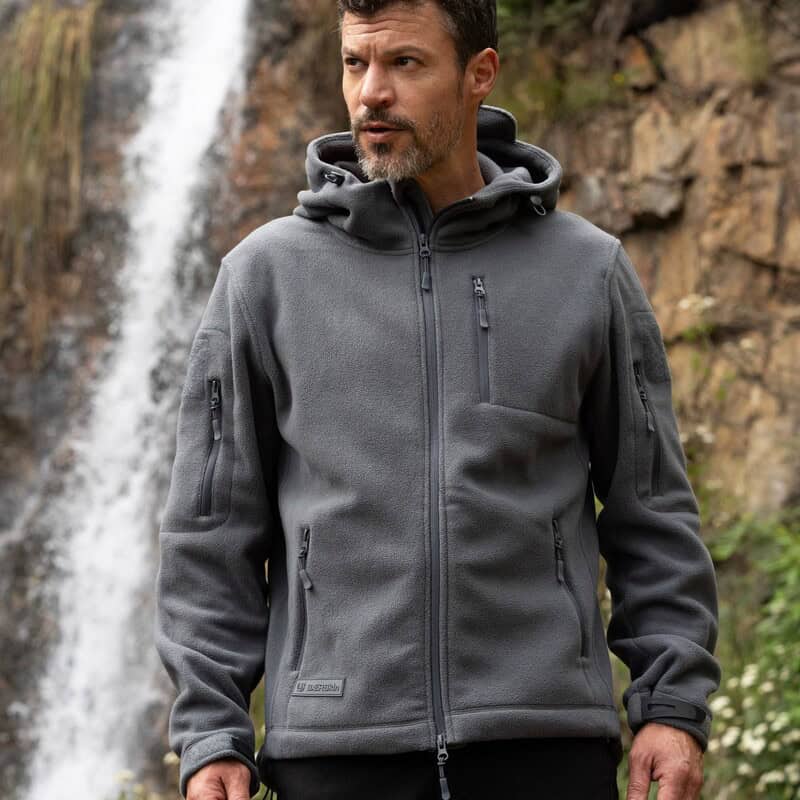 man wearing a baerskin tactical hoodie near a waterfall