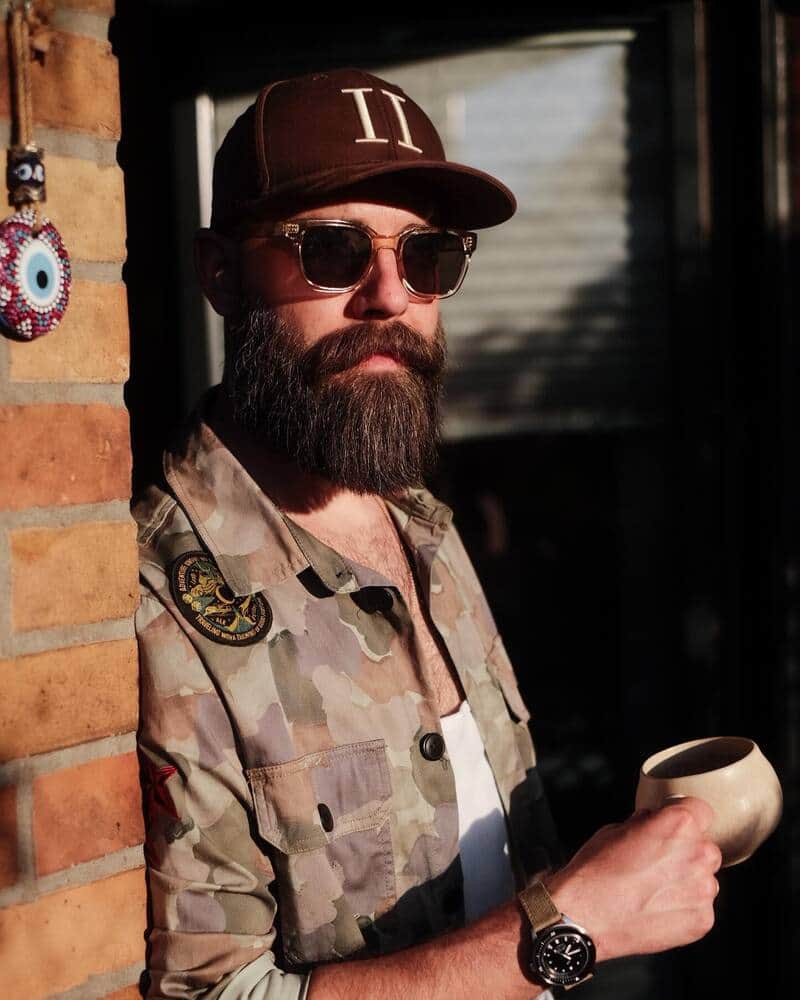 man with a long beard wearing a camo shirt and a maroon hat