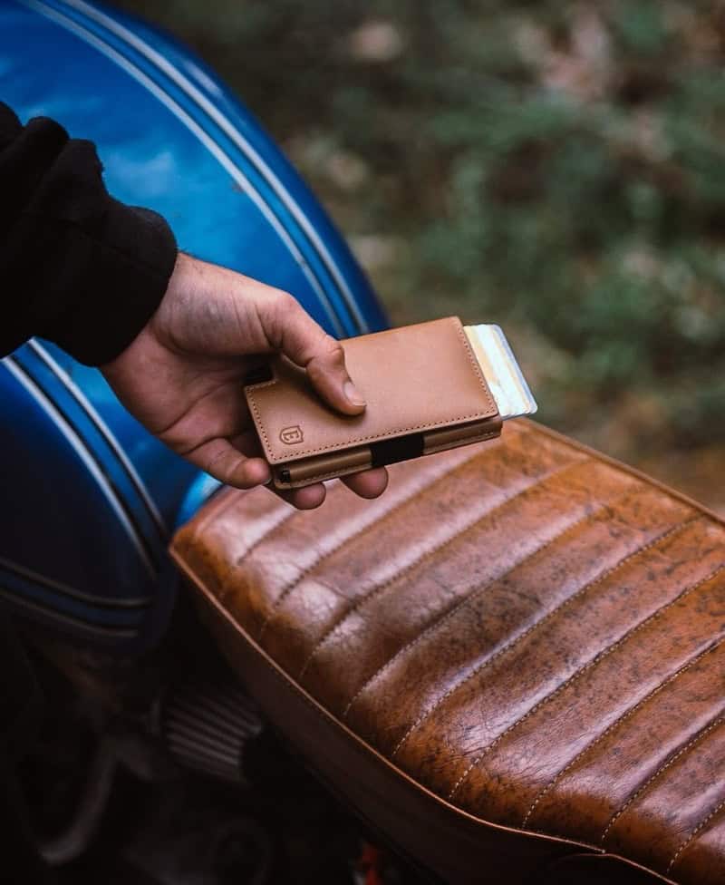 man holding a classic ekster wallet by a motorcycle