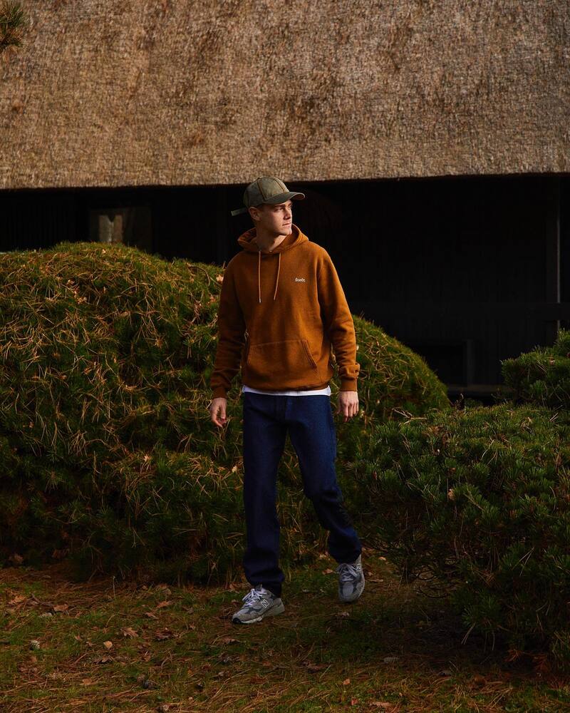 man wearing a brown hoodie by foret and jeans