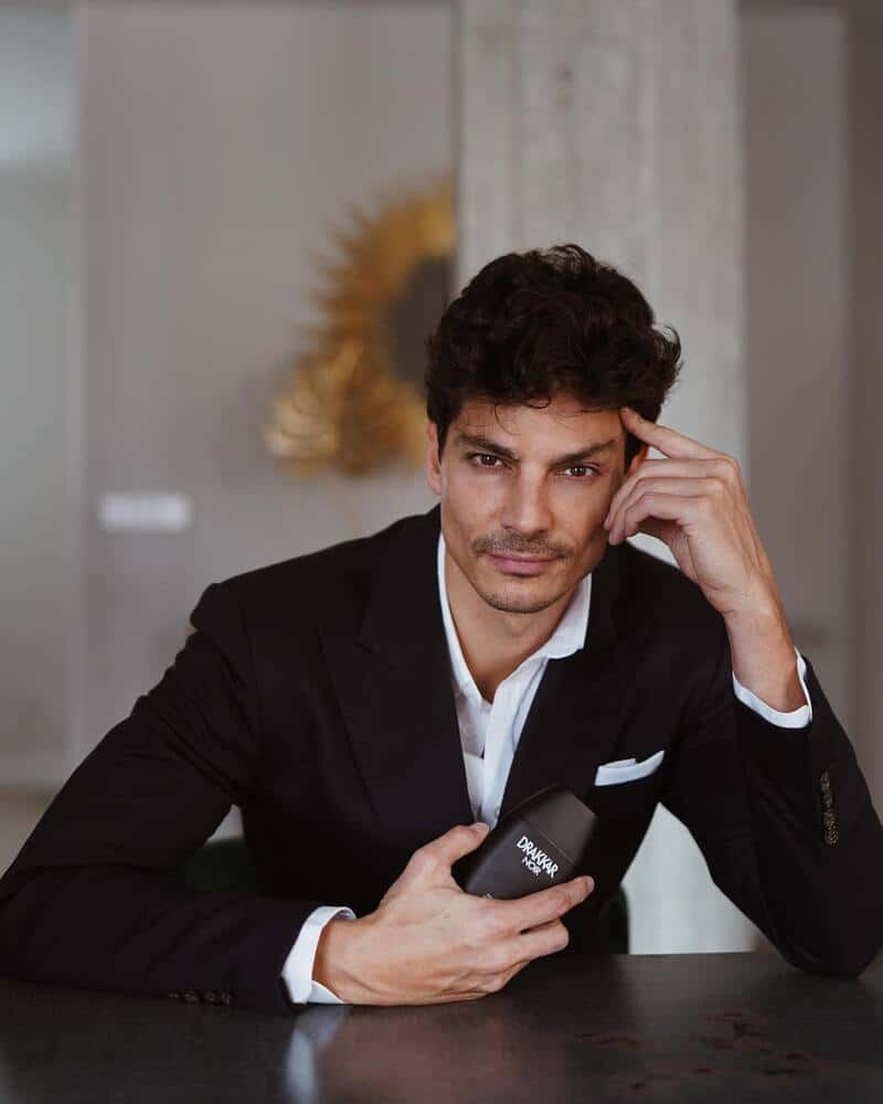 man on a table holding a bottle of drakkar noir cologne