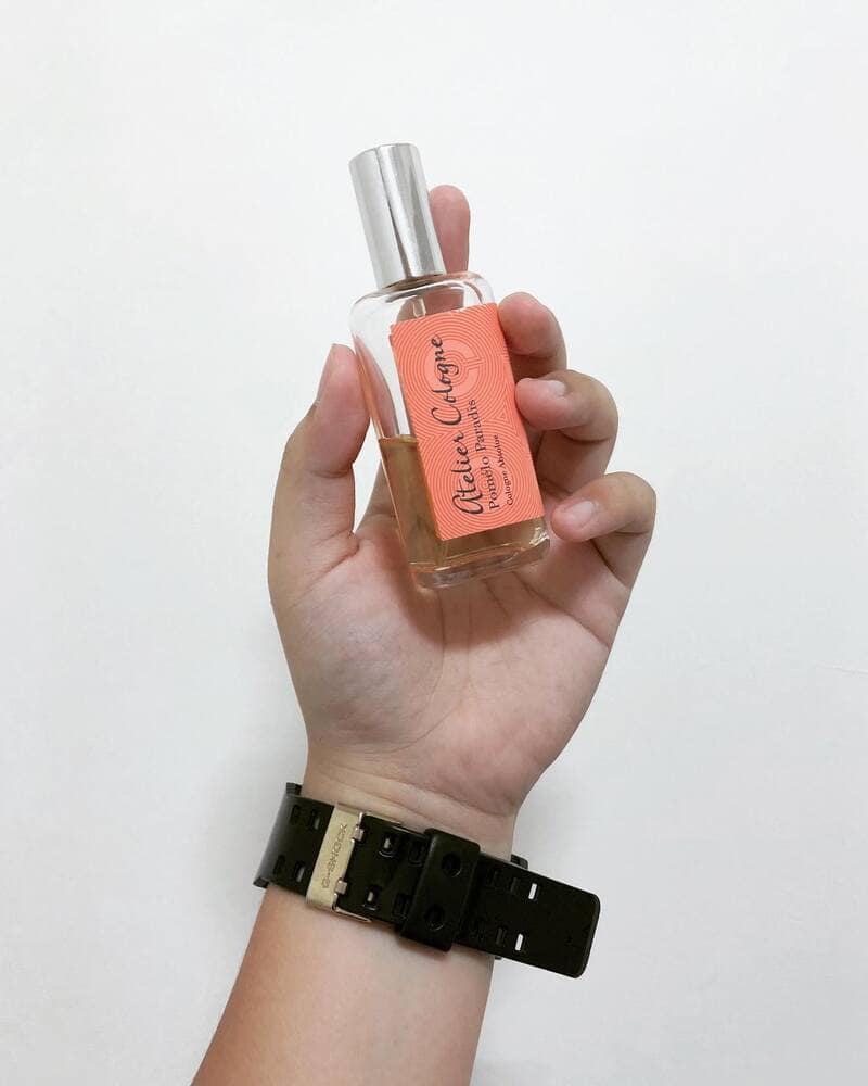 holding a bottle of Pomelo Paradise by Atelier Cologne