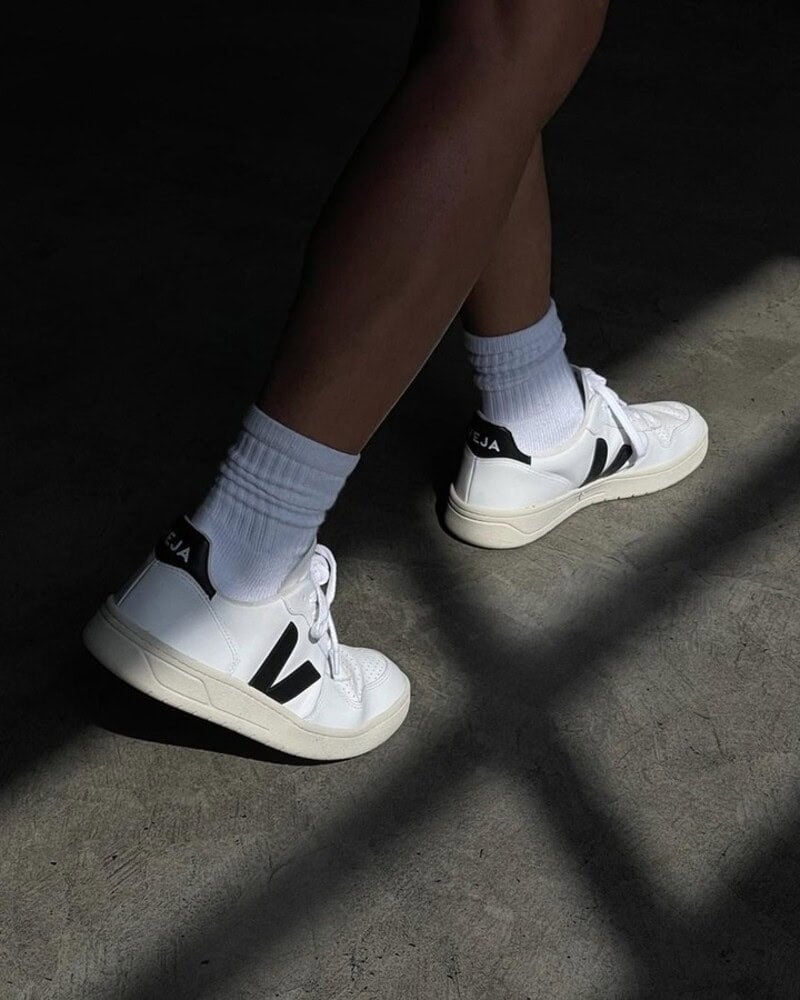 man walking wearing a pair of white socks and V10 white sneakers by veja