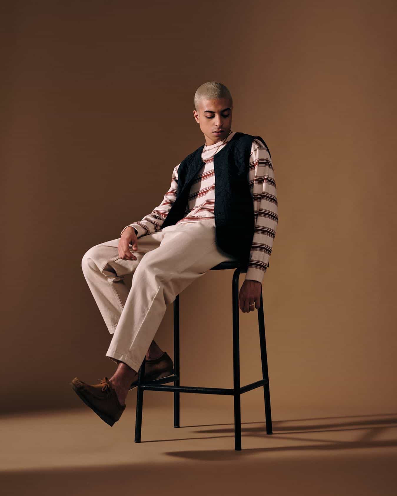 man sitting on a stool wearing a black quilted vest
