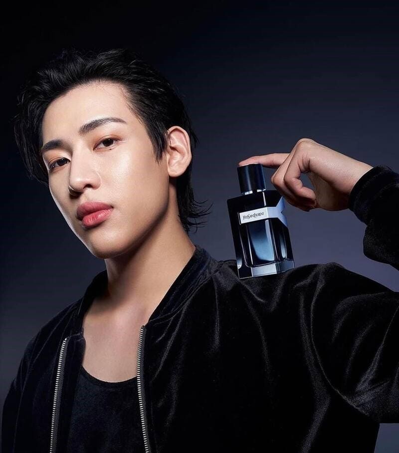 man holding a bottle of yves saint lauren to his shoulder