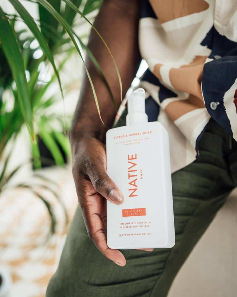 man holding a bottle of Citrus and Herbal Musk Daily Clean Shampoo by Native