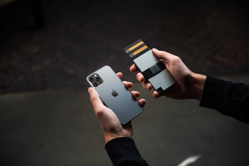 Man holding an iphone and an Ekster Cardholder