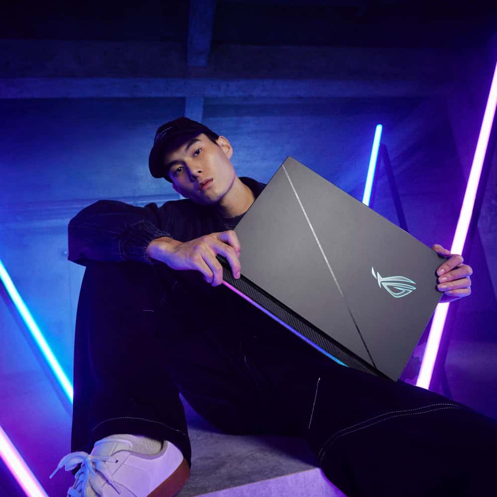 man holding an Asus ROG gaming laptop