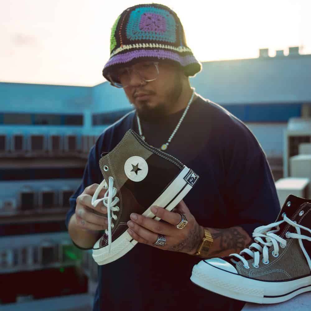 man holding a patchwork converse high tops