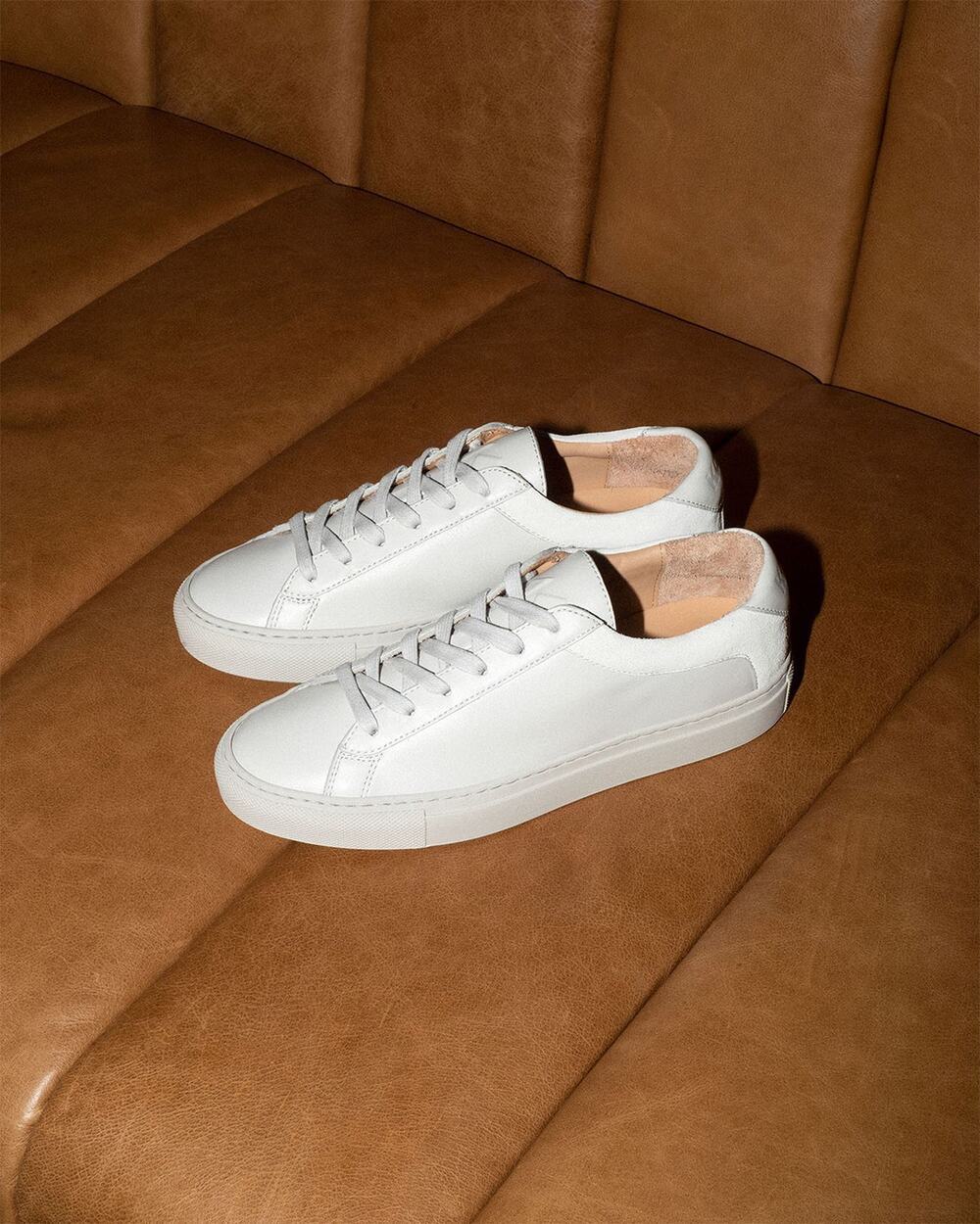 a pair of Capri Triple White by Koio on a couch