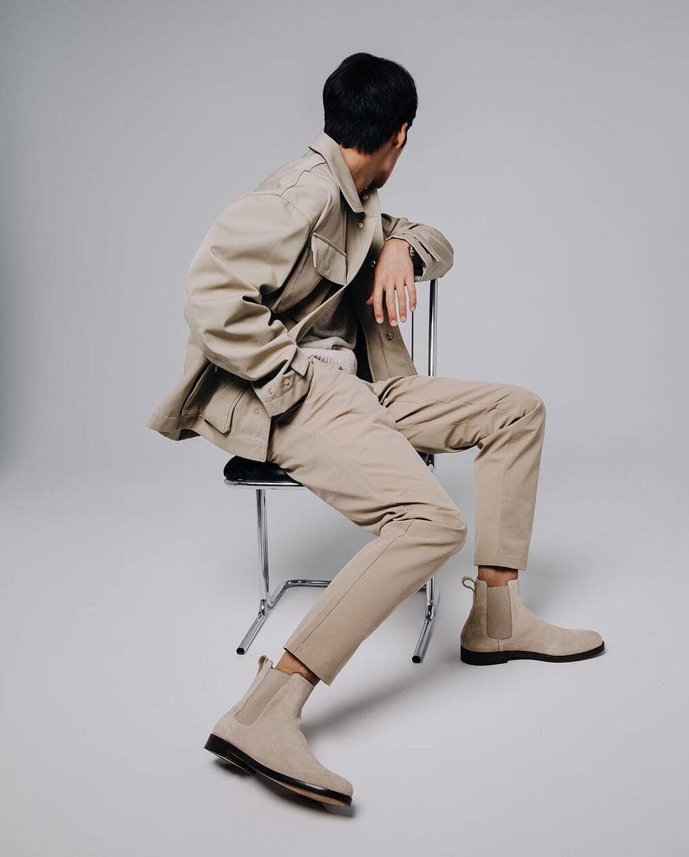 man sitting on a chair facing backwards and wearing a pair of chelsea boots