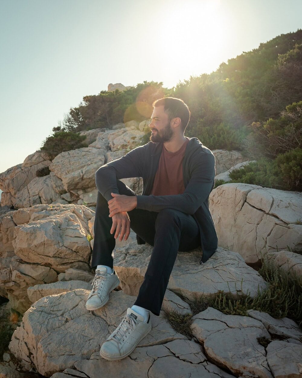 man sitting on a rock wearing the Travel Hoodie by Unbound Merino
