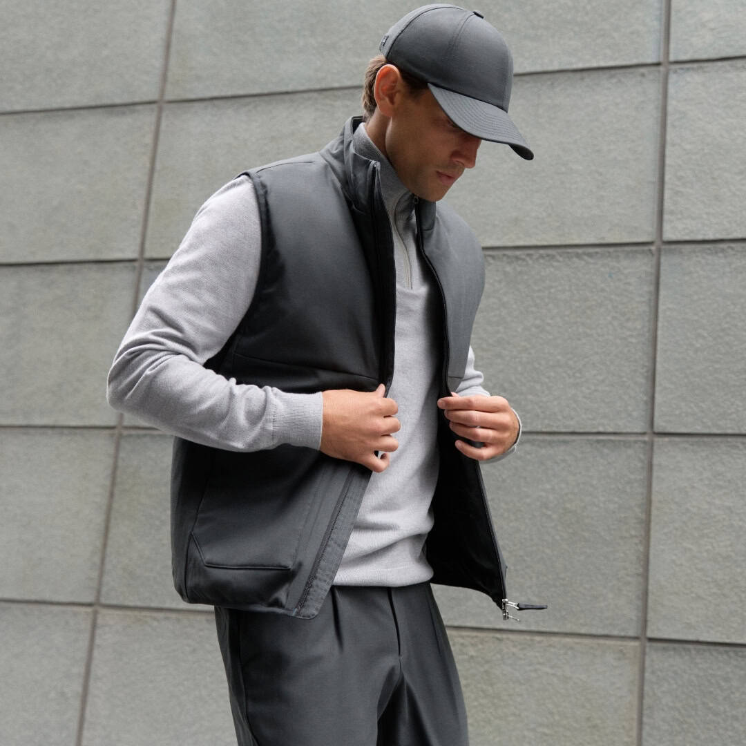 man wearing a grey wool vest and a hat