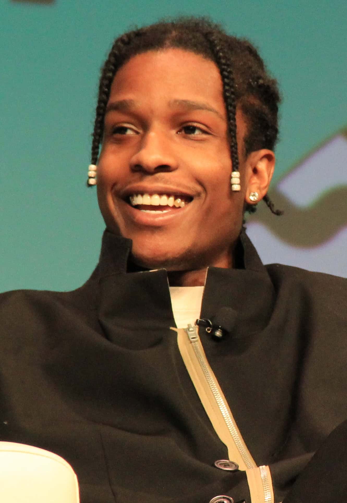 ASAP Rocky sitting on a couch wearing a black coat