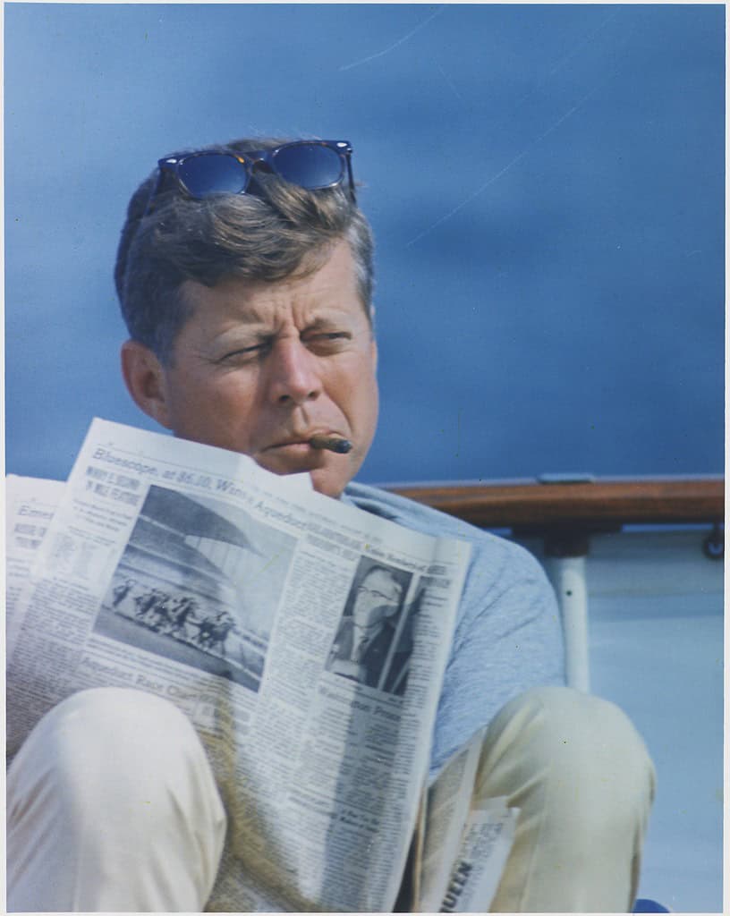 JFK with cigar and New York Times aboard the Honey Fitz