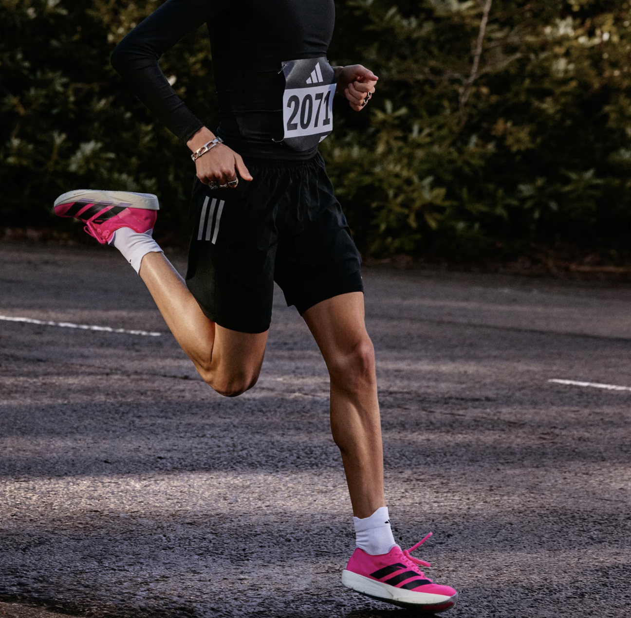 Running athlete wearing black athletic gear with pink running shoes during a race, weekly marathon or outdoor workout, emphasizing sportswear for running enthusiasts.